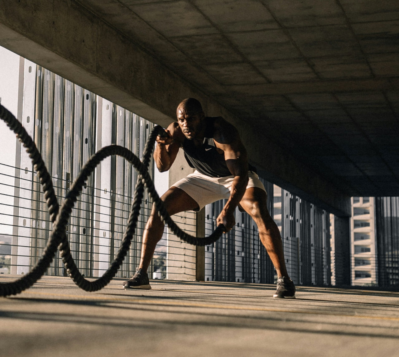 Athlete using battle ropes outdoors with urban background
